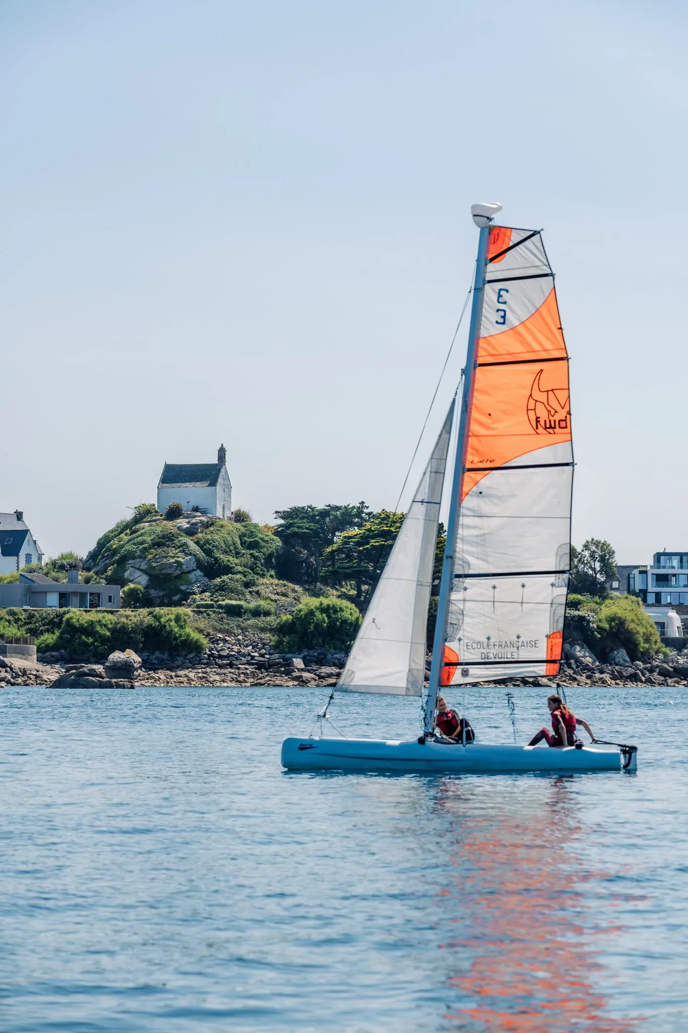 Catamaran du club sous voile avec deux jeunes équipiers, chapelle Sainte-Barbe en arrière-plan
