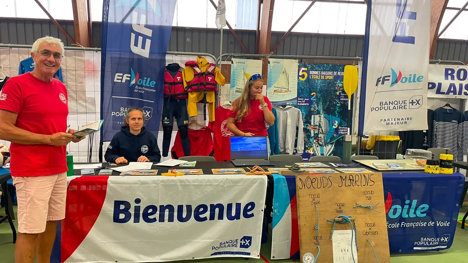 Trois bénévoles du Centre Nautique de Roscoff sur leur stand au forum des associations, derrière une banderole « Bienvenue »