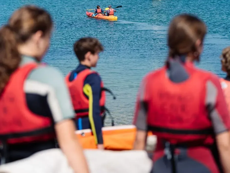 Young trainees rigging an Optimist on the slipway with their instructor