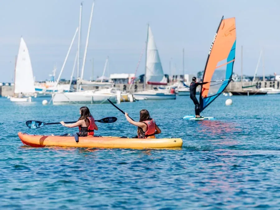 Club double kayak and windsurfing board on the harbour water